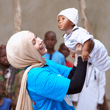 Volunteer lifting a child